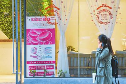 　4月11日，成都宏济巷的一家美容院，一位市民在张望活性酶净化治疗广告。本报记者杨树摄