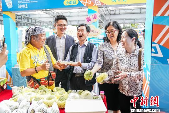 台湾歌手北原山猫吴廷宏(左一)和广西南宁市台协会长周代祥(左二)品尝台湾产的释迦果。　陈冠言 摄