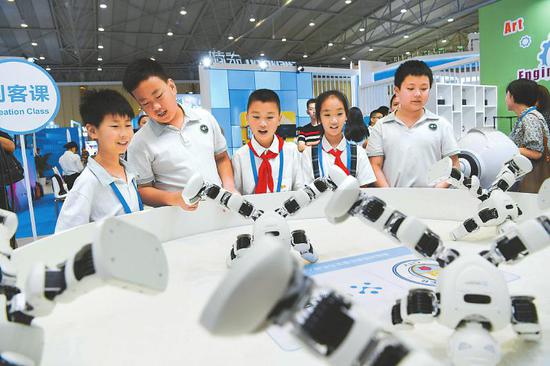 一款智能教育人形机器人吸引众多孩子围观。该款机器人能实现动作编辑和图形化编程，有利于锻炼孩子的动手能力、学习能力、逻辑思维能力。 　　本报记者 肖雨杨 摄