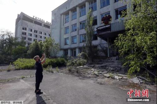 　　一名游客在切尔诺贝利核电站附近的废弃城市普里皮亚季拍摄一座建筑。