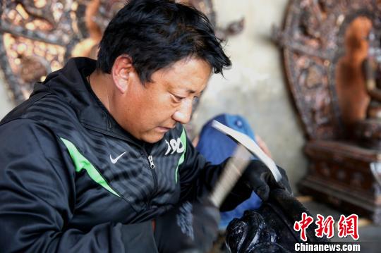 今年7月28日，文化和旅游部公布了首批全国乡村旅游重点村名单，西藏共有9个村被入选，其中拉萨市达孜区德庆镇白纳村榜上有名。图为白纳村铸铜雕刻艺人在塑像。　贡桑拉姆 摄