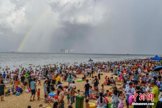 据官方统计，截至当日19时，共计有近10万人次的民众在假日海滩景区附近海边“洗龙水”，海边人头攒动如“下饺子”，场面十分壮观。中新社记者 骆云飞 摄