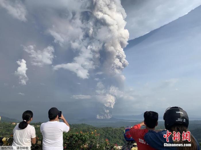 当地时间1月12日，菲律宾马尼拉西南卡维特省的塔盖泰镇，民众在给爆发的火山拍照。当地时间12日，菲律宾旅游胜地大雅台附近的塔尔火山开始喷发，火山灰高达10至15公里。