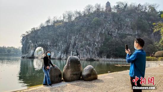 2月26日，广西桂林市象山景区正式对外恢复开放。这是广西桂林市21日宣布该市82个A级旅游景区向国内外疫情防控低风险地区游客有序开放的首个景区。图为来自广东的游客在象鼻山前拍照留念。 中新社记者 欧惠兰 摄